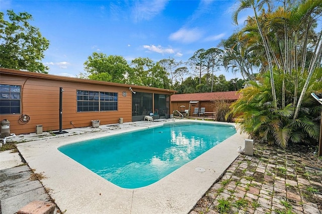 outdoor pool featuring a sunroom and a patio