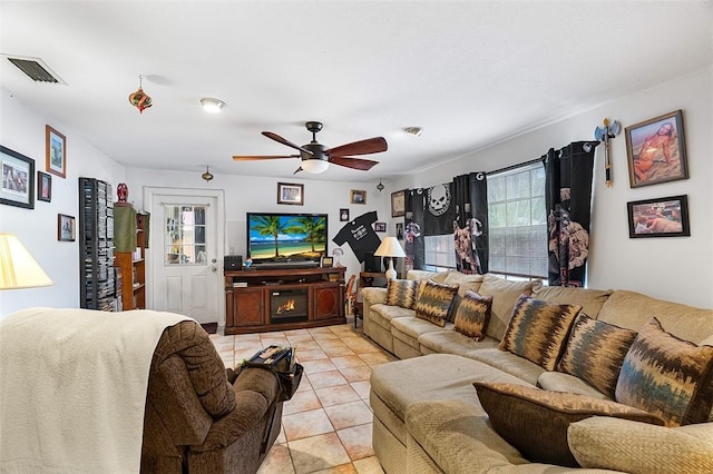 living room with light tile patterned floors, a fireplace, visible vents, and a ceiling fan