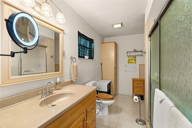 bathroom featuring a textured ceiling, tile patterned flooring, toilet, vanity, and a shower with door