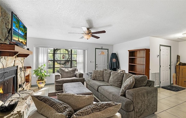 living room with light tile patterned floors, ceiling fan, a textured ceiling, a fireplace, and visible vents