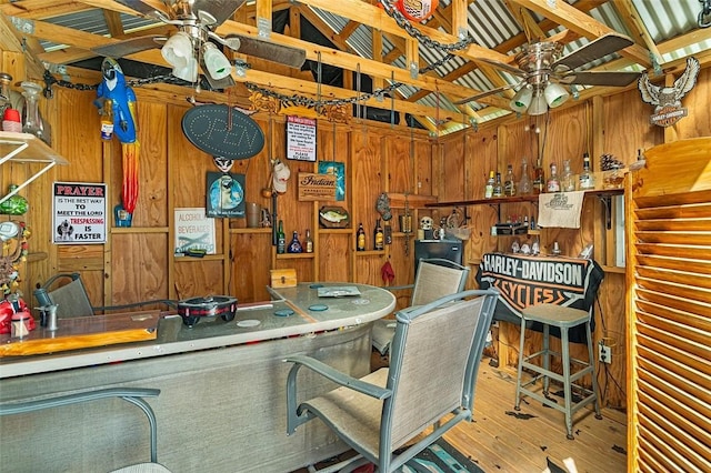 interior space with ceiling fan, wood finished floors, and wooden walls