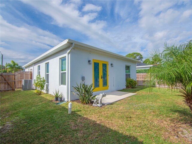 back of property featuring a lawn, cooling unit, and french doors