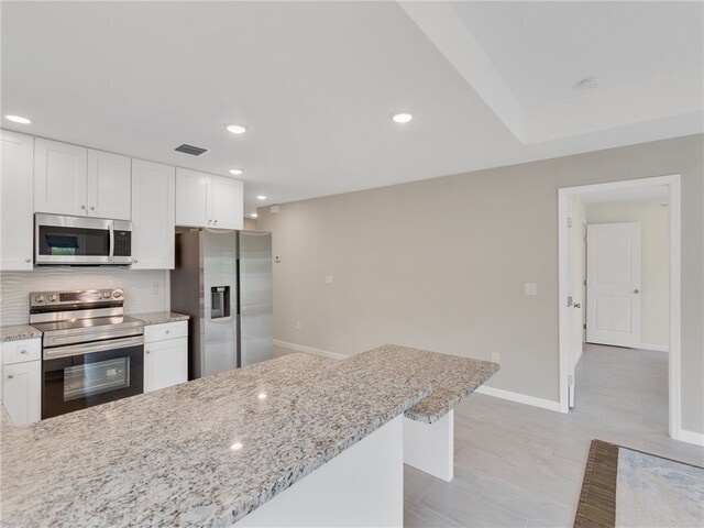 kitchen featuring white cabinets, appliances with stainless steel finishes, and light stone countertops