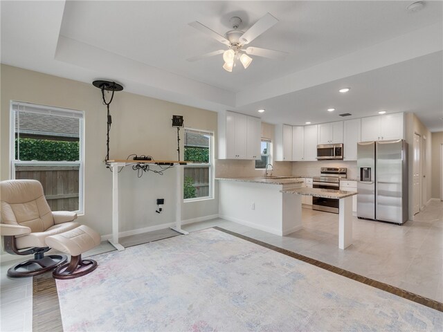 kitchen featuring kitchen peninsula, plenty of natural light, white cabinets, and stainless steel appliances