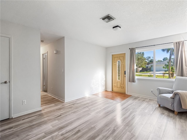 unfurnished room with light hardwood / wood-style floors and a textured ceiling