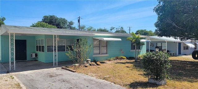 view of front of property with a front yard, a wall mounted AC, and a carport