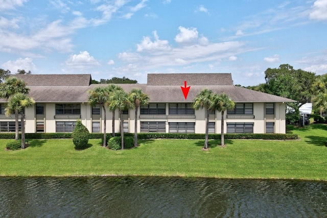 rear view of property featuring a water view and a lawn