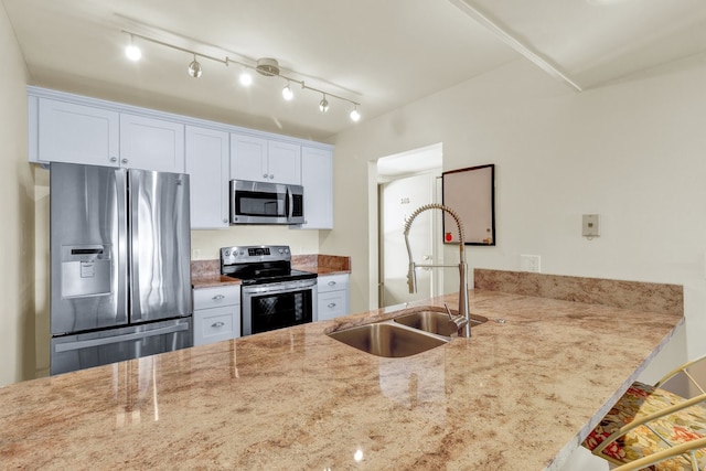 kitchen featuring a kitchen breakfast bar, light stone counters, stainless steel appliances, sink, and white cabinetry