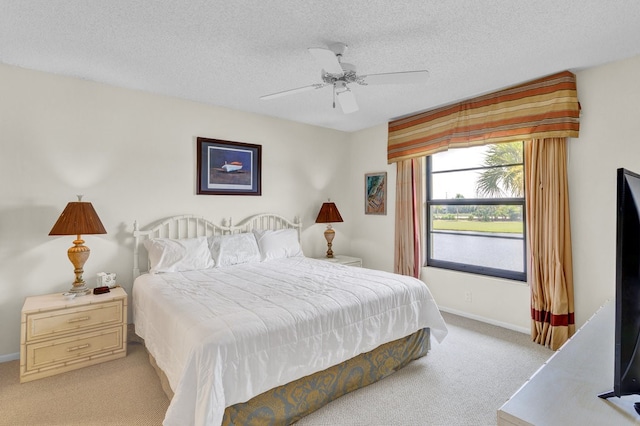 carpeted bedroom featuring ceiling fan and a textured ceiling