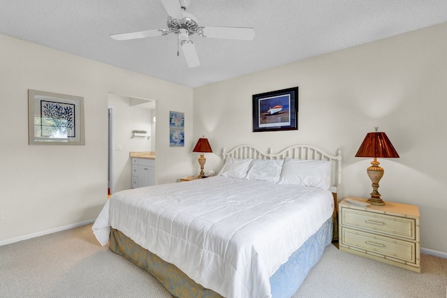 carpeted bedroom with ceiling fan, a textured ceiling, and ensuite bath