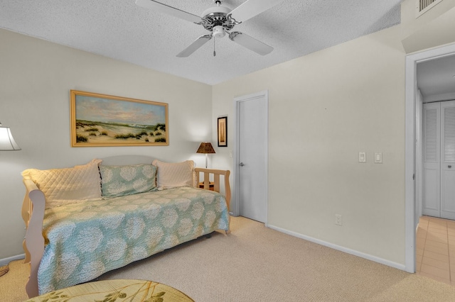 bedroom with a textured ceiling, ceiling fan, and light carpet