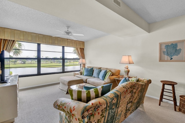 carpeted living room featuring ceiling fan and a textured ceiling