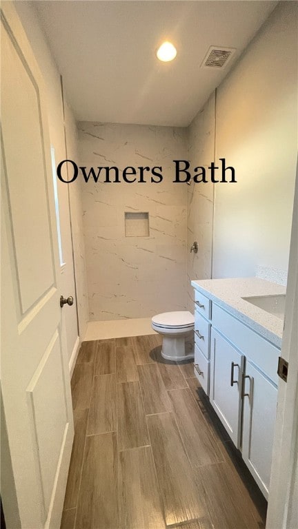 bathroom with vanity, toilet, and a tile shower