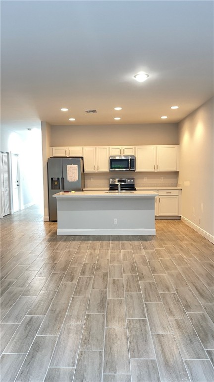 kitchen featuring white cabinets, a center island, light hardwood / wood-style floors, and stainless steel appliances