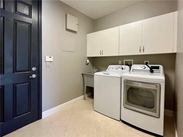 laundry room featuring cabinets, independent washer and dryer, and light tile patterned floors