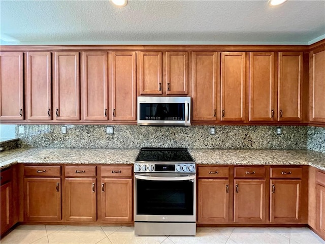 kitchen with tasteful backsplash, light tile patterned floors, stainless steel appliances, and a textured ceiling