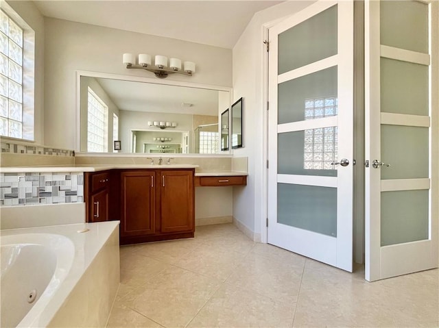 bathroom featuring plenty of natural light, vanity, a relaxing tiled tub, and tile patterned flooring