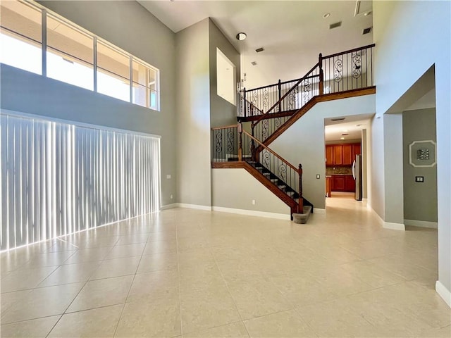 unfurnished living room featuring light tile patterned floors and a high ceiling