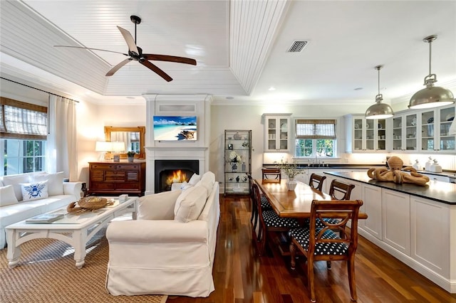 dining room featuring sink, ceiling fan, ornamental molding, dark hardwood / wood-style flooring, and a tray ceiling