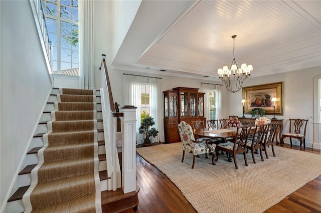 dining area featuring dark wood-type flooring, crown molding, and a chandelier