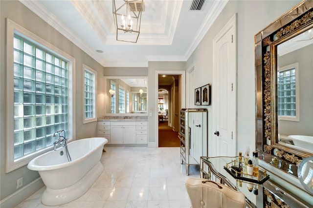 bathroom featuring a bathing tub, vanity, crown molding, a tray ceiling, and a notable chandelier