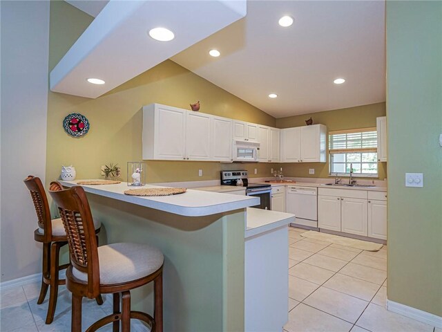 946 S Easy St, Sebastian, FL 32958 - kitchen featuring white appliances, a peninsula, a breakfast bar area, white cabinetry, and lofted ceiling
