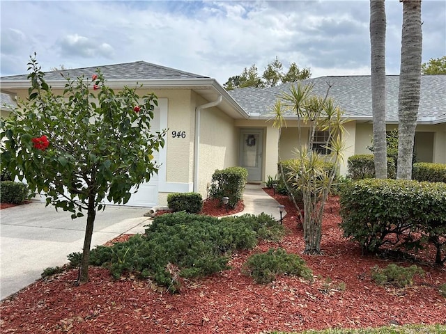 view of front of property with a shingled roof, an attached garage, and stucco siding