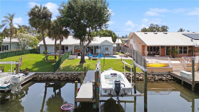 1933 Robalo Dr, Vero Beach, FL 32960 - dock with boat lift, a water view, a fenced backyard, and a patio area
