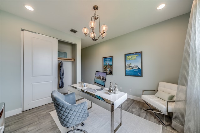 office with light wood-type flooring and an inviting chandelier