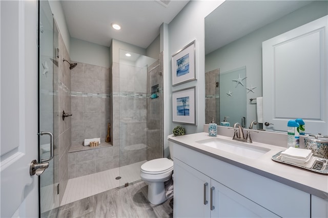 bathroom featuring vanity, an enclosed shower, and toilet