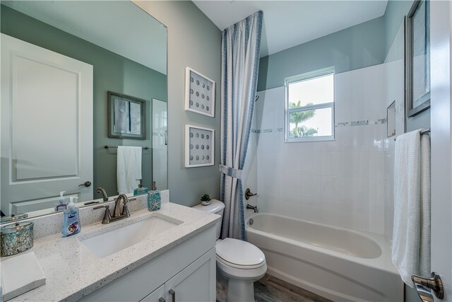 full bathroom featuring hardwood / wood-style floors, vanity, toilet, and shower / bath combo with shower curtain