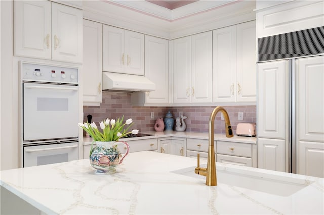 kitchen featuring paneled built in refrigerator, double oven, white cabinets, and under cabinet range hood