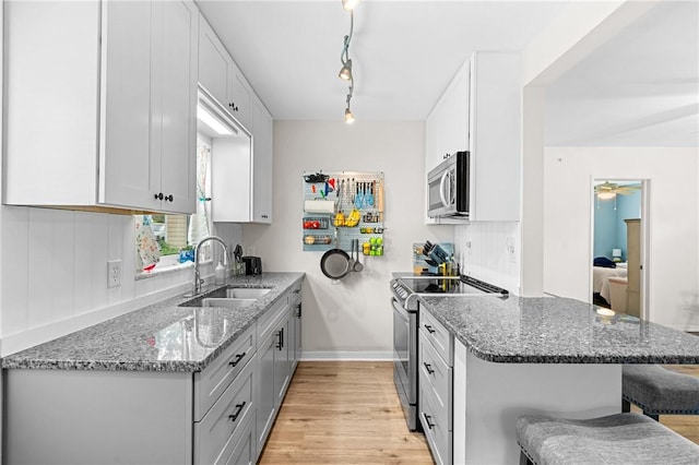 2106 36th Ave, Vero Beach, FL 32960 - kitchen with appliances with stainless steel finishes, a kitchen breakfast bar, light wood finished floors, a peninsula, and stone counters