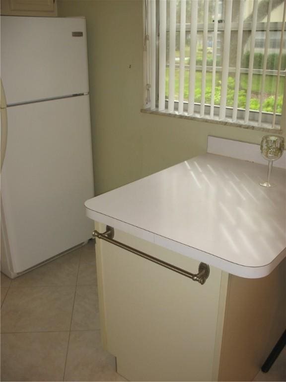 kitchen with light tile patterned floors and white refrigerator