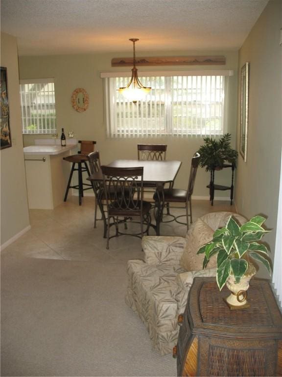 dining room with light carpet, a textured ceiling, and a chandelier