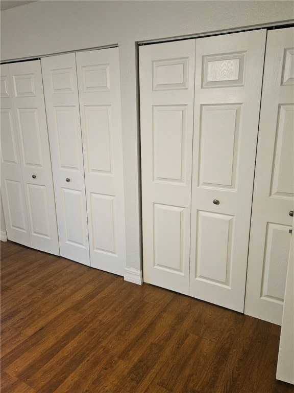 unfurnished bedroom featuring two closets and dark hardwood / wood-style flooring