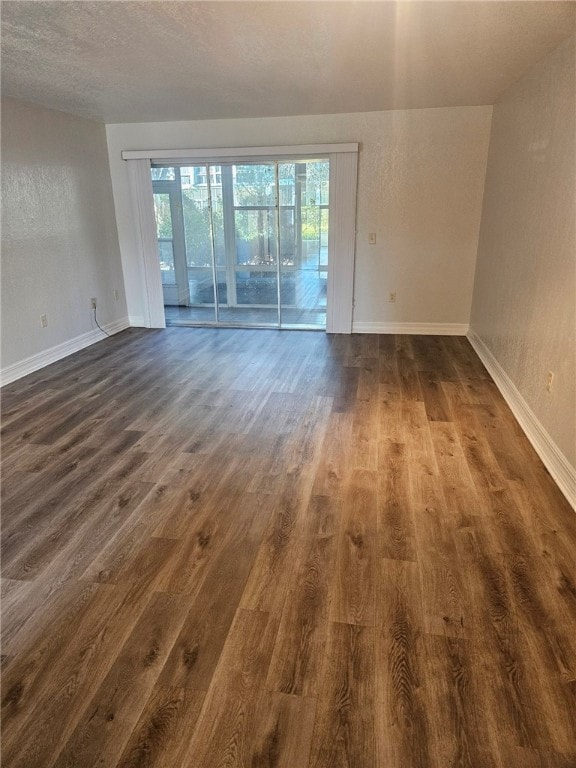 empty room with dark hardwood / wood-style flooring and a textured ceiling