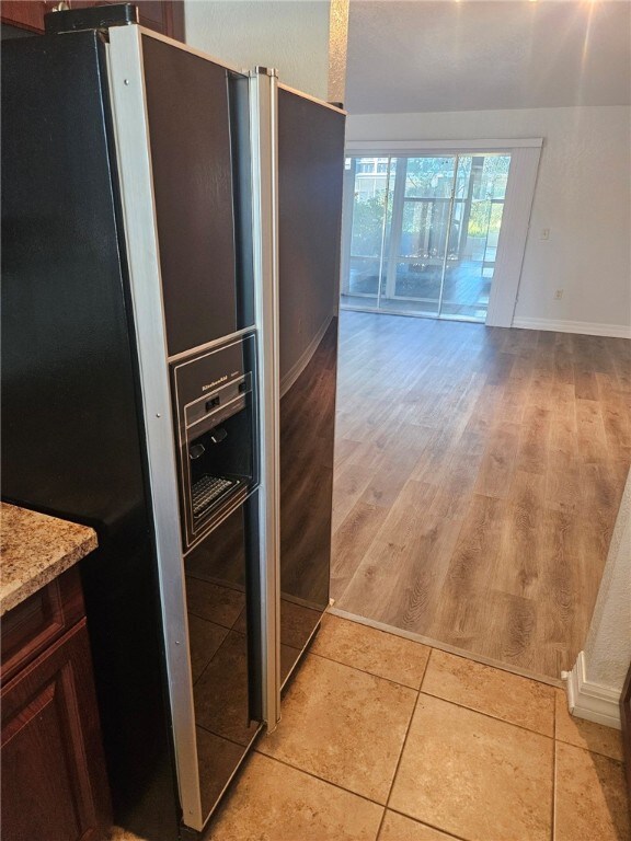 kitchen with dark brown cabinets, light hardwood / wood-style floors, and stainless steel refrigerator with ice dispenser