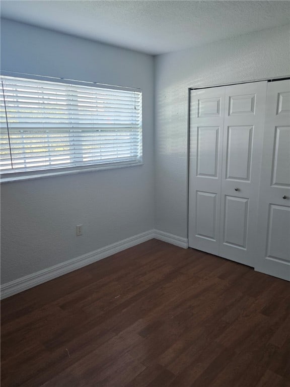 unfurnished bedroom with dark hardwood / wood-style flooring and a closet