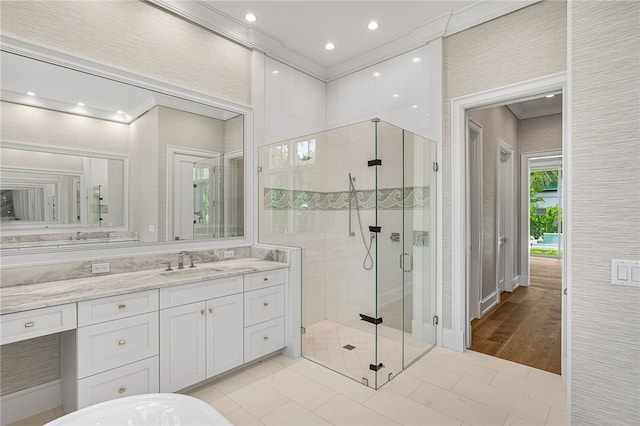 bathroom with hardwood / wood-style flooring, a shower with shower door, vanity, and ornamental molding