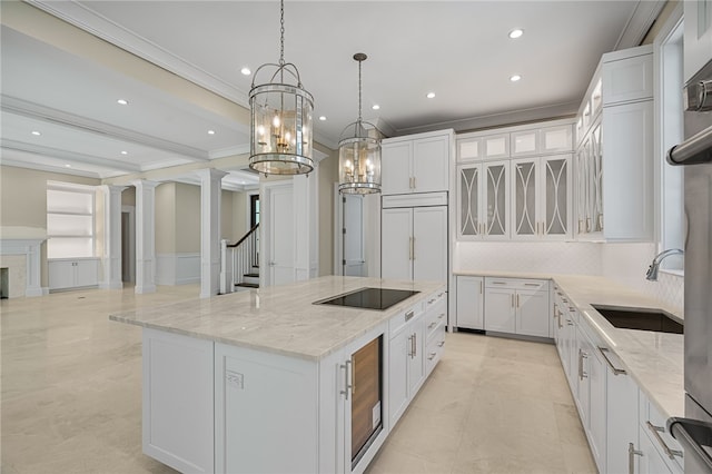 kitchen with white cabinetry, decorative light fixtures, a spacious island, decorative columns, and black electric stovetop