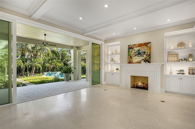 interior space with built in shelves, crown molding, beam ceiling, a premium fireplace, and ceiling fan