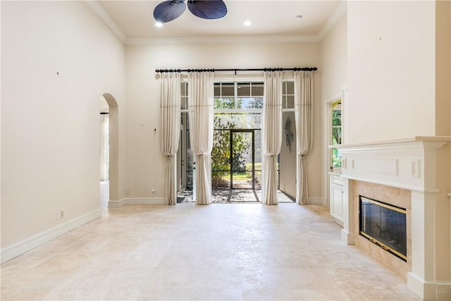 unfurnished living room featuring crown molding, a fireplace, baseboards, and ceiling fan