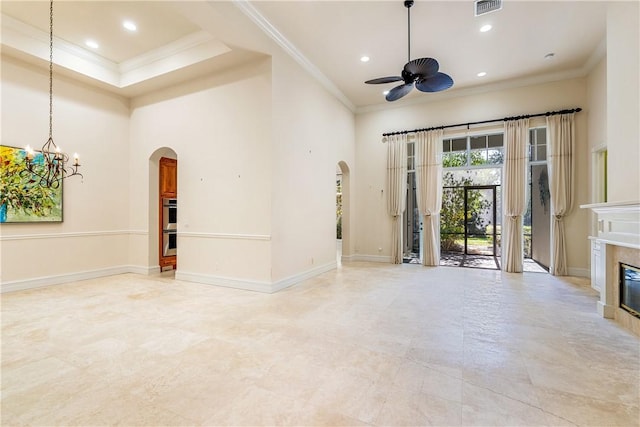 unfurnished living room with crown molding, ceiling fan with notable chandelier, arched walkways, and baseboards