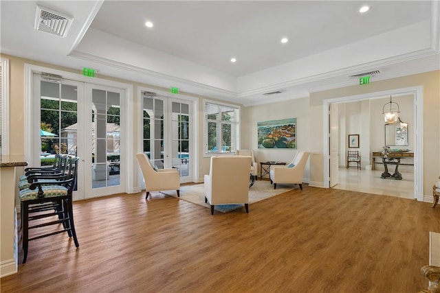 sitting room featuring visible vents, french doors, a raised ceiling, and wood finished floors