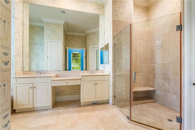 full bath featuring a sink, wallpapered walls, a shower stall, crown molding, and double vanity