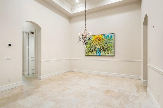 unfurnished room featuring an inviting chandelier, baseboards, arched walkways, and ornamental molding