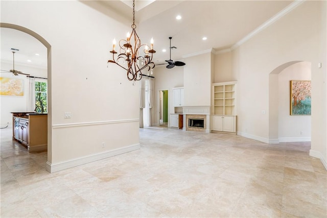 unfurnished living room featuring crown molding, baseboards, ceiling fan with notable chandelier, a high ceiling, and arched walkways