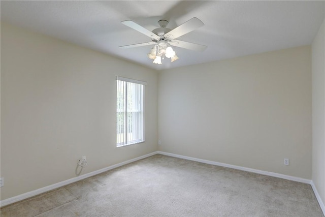 empty room with light colored carpet, baseboards, and a ceiling fan