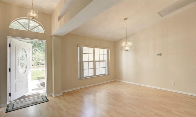 entryway featuring light wood finished floors, an inviting chandelier, and baseboards